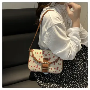 Detail of cherry print shoulder bag with brown leather strap and golden metal buckle