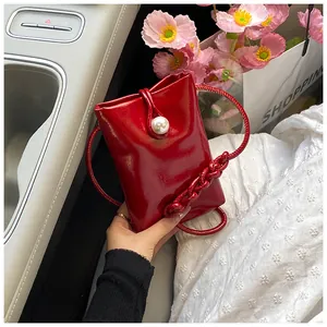 Detail of red patent leather mini crossbody bag with elegant pearl buckle closure