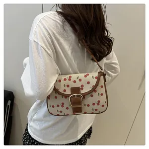 Detail of cherry print canvas bag with brown leather trim and golden buckle closure
