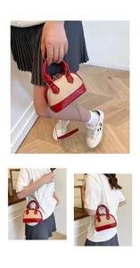 Detail view of mini shell bag showing woven straw and red leather contrast and chain strap