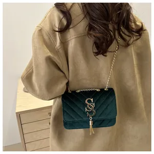 Detail of dark green velvet crossbody bag with V-quilted pattern and gold chain strap