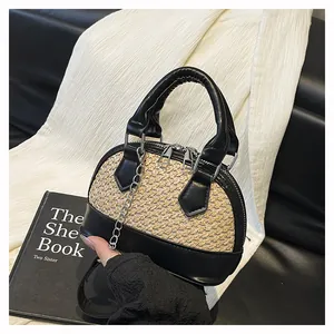 Detailed close-up of shell-shaped woven bag with black leather stitching and silver zippers