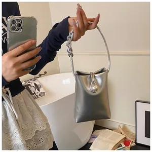 Detail of silver metallic handbag featuring a thick chain handle and a pearl decorative clasp