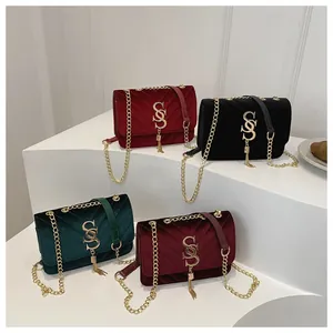 Close-up of velvet quilted chain bags with metal S-logo and tassels on white steps