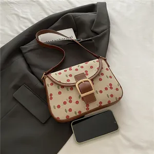 Vintage cherry print shoulder bag with brown leather trim and large gold metal buckle