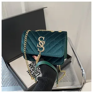 Close-up of dark green velvet bag featuring V-shaped quilting and gold chain tassel