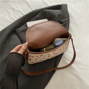 Chic cherry print underarm bag with brown leather trim and canvas texture on a blazer