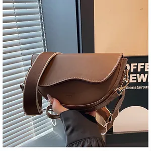 Détail du sac selle marron avec bordure de rabat ondulée et large bandoulière réglable