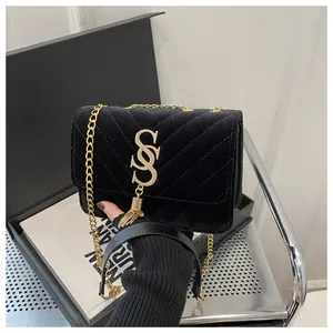 Detail of black velvet quilted bag with golden logo, fringe tassel and chain strap