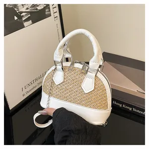 Detail of hand-held woven shell bag featuring white leather and straw patchwork design