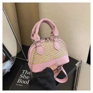Detail of pink PU leather and woven straw shell bag with silver dual zippers and handle