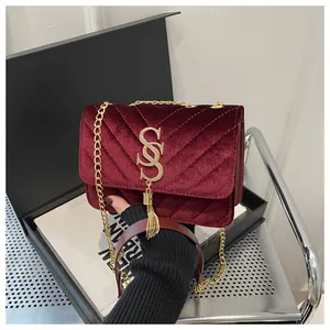 Detail of burgundy velvet crossbody bag with V-quilt pattern and gold tassel hardware