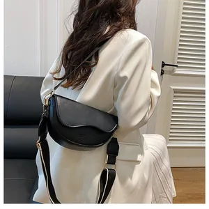 Vue latérale du sac selle en cuir noir mat avec large bandoulière tissée et boucle dorée