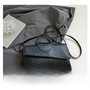 Detail of black snake pattern embossed leather envelope bag with silver circular handle