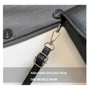 Detail of adjustable faux snakeskin strap and silver metal hardware on a black bag