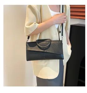 Detail view of snakeskin pattern patchwork clutch with metal ring handle and crossbody strap