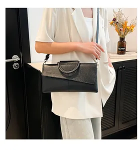 Model view of black leather envelope bag with snakeskin patch and metal D-handle detail