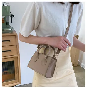 Chic khaki mini crossbody bag with gold hardware and dual handles worn on beige outfit