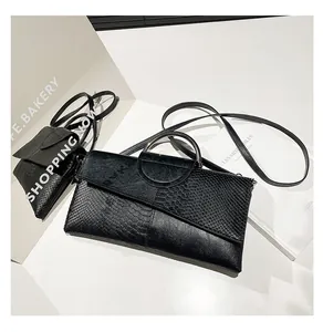 Detailed macro view of black snakeskin texture and silver ring handle on envelope bag