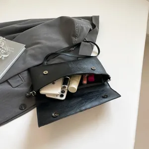 Black snakeskin patchwork envelope bag showing internal capacity with shoulder strap