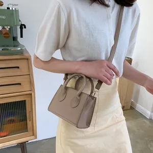 Minimalist beige mini crossbody bag with double top handles and sleek PU leather finish
