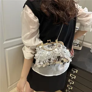 Silver sequin evening clutch bag with gold frame and chain strap shown on a model