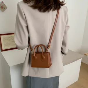 Chic caramel brown mini crossbody bag in smooth leather with round top handles and strap