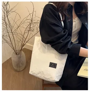 Detail of white nylon tote bag showing FANYISSA label and soft crinkled texture