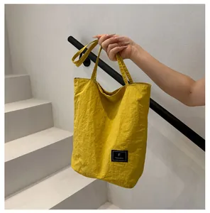 Detailed close-up of vibrant yellow nylon tote with a black brand label and pleated texture