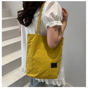 Close-up of yellow nylon tote bag featuring natural crinkle texture and brand label