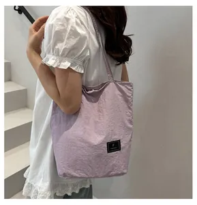 Macro detail of purple nylon tote bag featuring a square black logo tag and textured fabric
