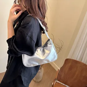 Borsa sottobraccio a mezzaluna argento metallizzato indossata da una modella in un interno