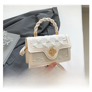 Detail of floral embossed texture with gold flower lock and braided handle on cream handbag