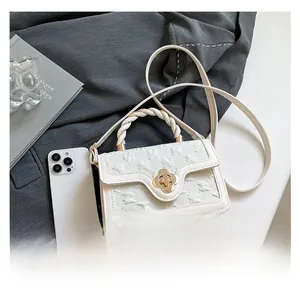Detail of white mini handbag featuring textured fabric and golden clover lock closure