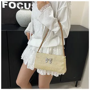 Détail du sac bandoulière en paille avec nœud métallique et lanière en cuir