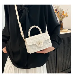 Detail of cream white quilted handbag with a twist handle and floral clasp on a model