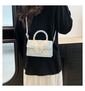 Detail of light blue and beige woven crossbody bag with golden flower lock on the model