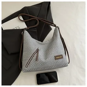 Detalle del tejido de espiga y bolsillo metálico en un bolso tote de estilo minimalista