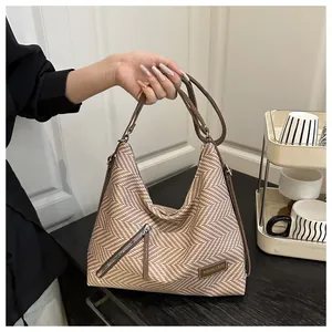Detalle del bolso hobo de tela de espiga con correas de cuero y etiqueta de moda
