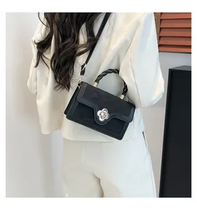 Detail of black crossbody bag featuring floral silver clasp and braided top handle texture