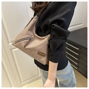 Detalle del bolso hobo en tejido de espiga con cremallera vintage y correa de cuero marrón