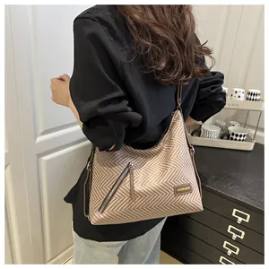 Detalle del bolso tote tejido con bolsillo con cremallera diagonal y correa de cuero marrón