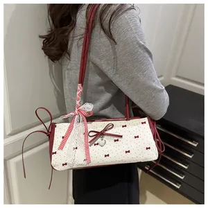 Shoulder bag detail featuring red polka dots on white canvas with ribbon charms