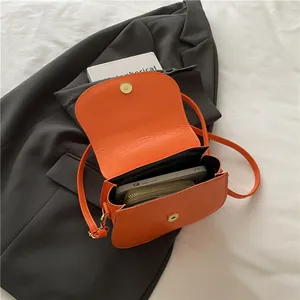 Bright orange PU leather saddle bag with magnetic closure shown with smartphone inside