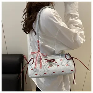 Detail of light blue underarm bag featuring red bow patterns and lace shoulder strap