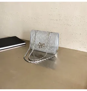 Détail du sac bandoulière argenté matelassé avec boucle nœud et bandoulière chaîne
