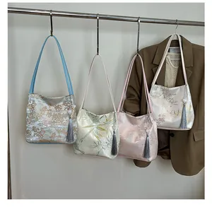 Detailed view of jacquard embroidered shoulder bags in four colors with pearl tassels