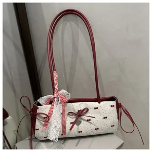 Detail of canvas shoulder bag with red polka dots, lace bow, and metal heart pendant