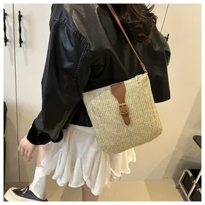 Detail showing the straw crossbody bag with brown leather trim and vintage buckle on the side
