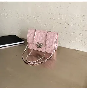 Détail du sac matelassé rose clair avec fermoir nœud argenté et bandoulière en chaîne